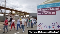 Вакцина пунктінің маңында кетіп бара жатқан адамдар. Көрнекі сурет.