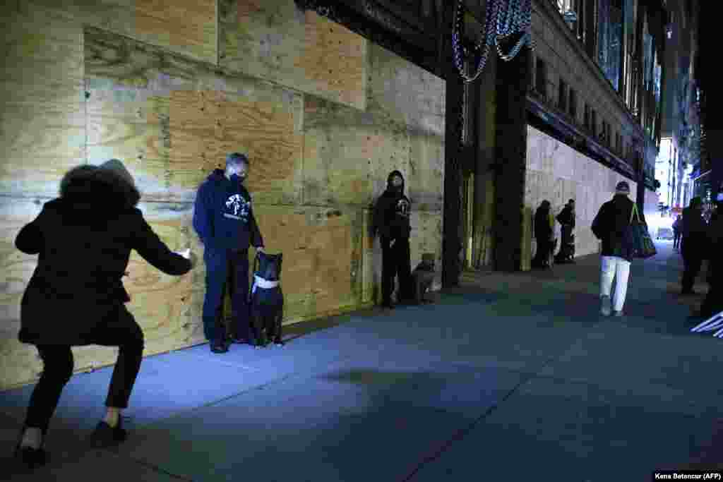 Приватні охоронці стоять біля забитого дошками універмагу Saks Fifth Avenue ввечері перед президентськими виборами в Нью-Йорку. 2 листопада 2020 року