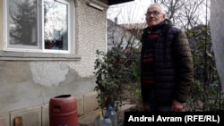 Eugen Tusică (74 de ani), pensionar în comuna Bănești (Prahova), lângă butoiul cu apă de ploaie care-l ajută să treacă mai ușor prin criza provocată de sistarea apei curente.