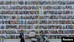 مردی از کنار تصاویر گروگان های ربوده شده در جریان حمله مرگبار حماس در ۷ اکتبر در تل آویو می گذرد.