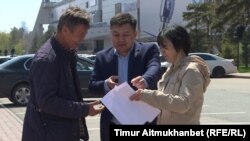 Представитель акимата Астаны (в центре) передает подавшим заявку на проведение митинга 21 мая «по земельному вопросу» письменный отказ. Астана, 18 мая 2018 года. 