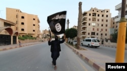 Сириянын Ракка шаарында “Ислам мамлекети” тобунун согушкери ИМдин желеги менен.