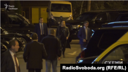 Охоронець веде жінку до автівки, зареєстрованої на ГПУ