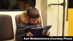 Метродо китеп окуп бараткан бала.