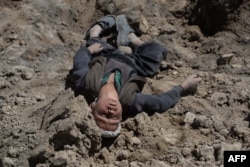 Мальчик, потерявший всю семью, лежит на месте, где погребены его родные