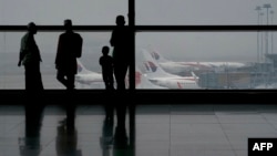 Куала Лумпур әуежайында Malaysia Airlines компаниясы ұшақтарына қарап тұрған адамдар. Малайзия, 13 наурыз 2014 жыл. (Көрнекі сурет)