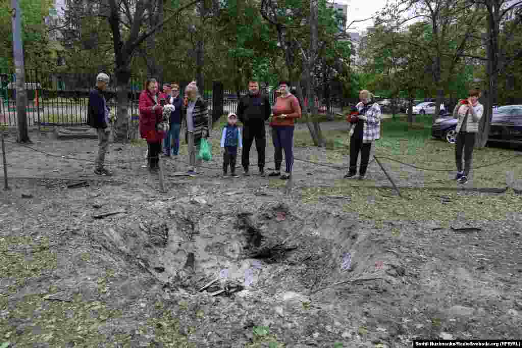 Киевляне возле одной из воронок в Оболонском районе, возникшей в результате российского удара, 4 мая 2025 года