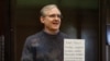 Paul Whelan holds up a sign denouncing the legal proceedings against him as he stands inside the defendant's cage during a court hearing in Moscow on June 15.