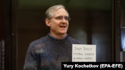 Paul Whelan holds up a sign denouncing the legal proceedings against him as he stands inside the defendant's cage during a court hearing in Moscow on June 15.