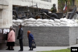 Ресейшіл сепаратистер басып алған облыстық әкімшілік жанында референдум туралы хабарландыру оқып тұрған адамдар. Донецк, 9 мамыр 2014 жыл.