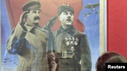 Посетитель выставки «Победа» смотрит на плакат с изображением Иосифа Сталина. Москва, 23 апреля 2010 года.