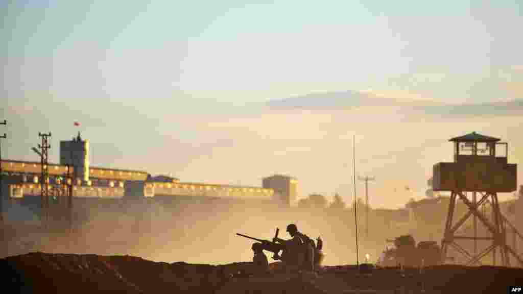 Турецкая армия на границе с Сирией после того, как сирийский самолет сбросил бомбу на занятый повстанцами пограничный с Турцией город Рас аль-Аин 12 ноября. (AFP/Булент Килич)