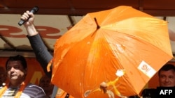 Жумуртка - "пролетариаттын куралы". Европарламенттин шайлоо өнөктүгү маалында Чехиянын социал-демократтык партиясынын мүчөсү Давид Рац жана Европарламентке депутаттыкка талапкер Йиржи Гавел атаандаштары ыргаткан жумурткадан кол чатыр менен коргонушууда. П