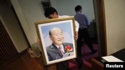 Последователь Муна несет его портрет к алтарю во время поминальной церемонии в Церкви объединения