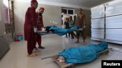 Afghan medical workers carry the bodies of two foreign women who were shot dead in Herat on July 24. 