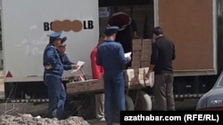 Türkmenistanda polisiýa işgärleri ýük ulagyna ýüklenýän harytlary barlagdan geçirýärler. (Illýustrasiýa suraty)