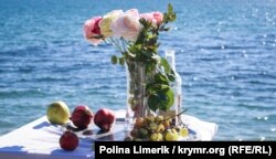 Деңиз жээгиндеги ваза, гүл, мөмөлөр.