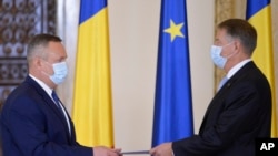 Romanian President Klaus Iohannis (right) receives the signed oath from Prime Minister-designate Nicolae Ciuca during a swearing-in ceremony in Bucharest on November 25.