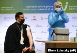 Золотоверхий (Алтын күмбөздүү) украин ортодокс христиан чиркөөсүнүн архимандрити Лврентий (Живчик) мырза "AstraZeneca" компаниясынын Индияда өндүрүлгөн "Ковишилд" ( Covishield ) түрү менен эмделди. Киев, Украина. 2021-жылдын 16-марты.