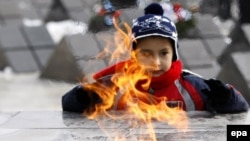 Румынский мальчик, родственник жертвы восстания 1989 года, стоит у Вечного огня, зажженного на Кладбище Революции в городе  Тимишоара. 17 декабря 2009 года. 