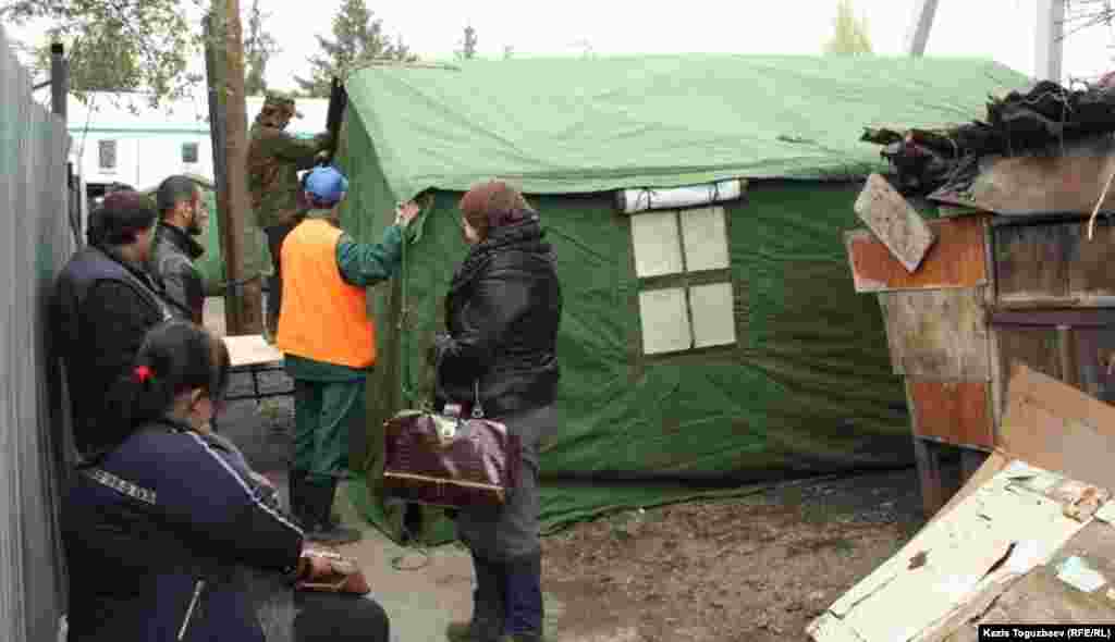 Сотрудники службы спасения устанавливают палатку. Погорельцы наблюдают за процессом. 