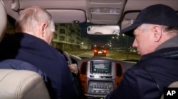 На цьому фото, взятому з відео, опублікованому російським ТБ у неділю, 19 березня 2023 року, президент Росії Володимир Путін (за кермом) і віце-прем’єр-міністр Росії Марат Хуснуллін їдуть на автомобілі окупованим Маріуполем. Перед цим Путін прибув до окупованого Криму, щоб « відзначити дев'яту річницю анексії» українського півострова.