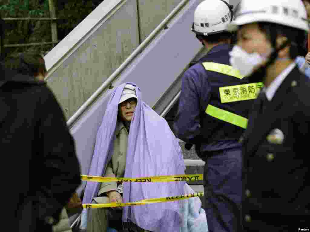 Japan - A man sits wrapped in a blanket after he was evacuated from a building in Tokyo's financial district, after an earthquake off the coast of northern Japan, 11Mar2011 - Человек сидит, завернутый в одеяло, после того, как он был эвакуирован из здания в финансовом районе Токио.  REUTERS / Kim Kyung-Hoon 