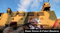 Liwiýanyň Milli armiýasynyň söweşijisi öz ýaragyny Rejep Erdoganyň portretine gezäp dur. Sirt şäheri, 2020-nji ýylyň iýuly.