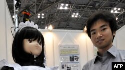 Сайтама университетинин профессору Юшинори Кобаяши роботторго арналган көргөзмөдө робот менен конокторго шоколад таратып жүрөт. Токио. 29-июль, 2010