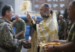 Священник Московського патріархату благословляє російського полковника Ігоря Гіркіна (Стрєлкова), який на той час був одним із ватажків угруповання «ДНР». Окупований Донецьк, 10 липня 2014 року