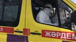 Медики в защитных костюмах в машине скорой помощи.