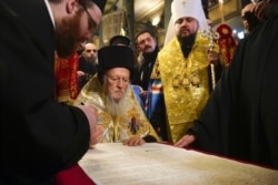 Вселенський патріарх Варфоломій підписує томос про автокефалію для Православної церкви України (ПЦУ). По ліву руку від нього стоїть митрополит Київський і всієї України Епіфаній. Стамбул, 5 січня 2019 року