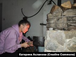 Катерина розпалює вогонь у печі в підвалі