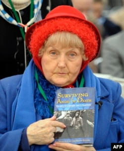 Ева Мозес Кор показывает на фотографию себя и своей сестренки-близнеца на обложке книги об Освенциме.