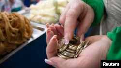 Монеты в руках продавца на рынке в Алматы.