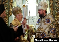 Вселенський патріарх Варфоломій (ліворуч) в момент передання главі Православної церкви України митрополиту Епіфанію томосу про автокефалію. Стамбул, 6 січня 2019 року