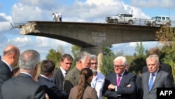 У правій частині фото керівники МЗС Німеччини і Франції – Франк-Вальтер Штайнмаєр (в рожевій краватці) та Жан-Марк Еро – неподалік Слов’янська біля моста, який був підірваний влітку 2014 року за наказом одного з ватажків угруповання «ДНР», російського полковника Ігоря Гіркіна. 15 вересня 2016 року