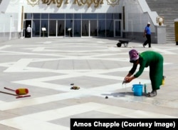 Женщина чистит плитку на проходе перед дворцом бракосочетаний в Ашхабаде