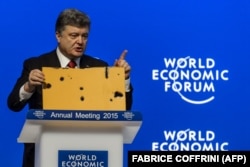 Президент України Петро Порошенко демонструє фрагмент пасажирського автобуса, який був знищений ракетним ударом російських гібридних сил на околиці Волновахи 13 січня 2015 року. Внаслідок нападу загинули 12 (за іншими даними, 13) людей, ще 18 були поранені. Давос, 21 січня 2015 року