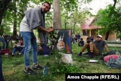 A man places a flower onto an upside-down portrait of Prime Minister Serzh Sarkisian in a children’s park in Yerevan. The frame features a black strip of cloth at the corner, traditionally placed over a portrait when someone is dead.