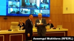 Кандидат от движения "Ұлт тағдыры" Амиржан Косанов показывает удостоверение кандидата, врученное ему председателем ЦИК Бериком Имашевым (слева). Нур-Султан, 6 мая 2019 года.