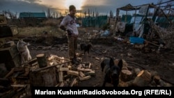 Український військовослужбовець із позивним «Піксель» рубає дрова посеред села Піски