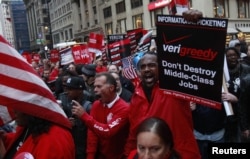 Дүйнөдөгү эң ири телекоммуникациялык Verizon Communications компаниясынын кызматчылары "Уолл-стритти ээле!" кыймылына тилектештик билдирип, Зукотти сейил багында демонстрация өткөрүшүүдө. Нью-Йорк, 21-октябрь, 2011