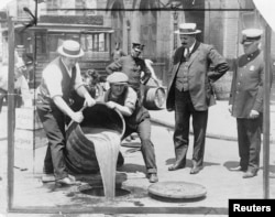 Заместитель комиссара полиции Нью-Йорка Джон Лич наблюдает, как его агенты уничтожают спиртное