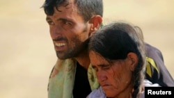 Iraq -- A displaced man and a woman from the minority Yezidi sect, fleeing violence from forces loyal to the Islamic State in Sinjar town, walk towards the Syrian border, on the outskirts of Sinjar mountain, 11 August 2014.