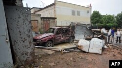 Местные жители стоят возле автомобиля, уничтоженного после столкновений между украинскими войсками и пророссийскими боевиками. Луганск, 19 июля 2014 года