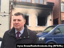 Йосип Борто на тлі будівлі після підпалу