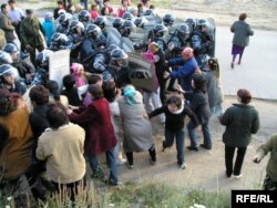 Полицейские силой прорвали кордон женщин, преградивших им путь в поселок Шанырак близ Алматы. 14 июля 2006 года.