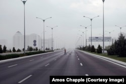 Дворник подметает одну из крупных автотрасс. Дорога, ведущая из города, пуста перед надвигающимся на город штормовым дождем.