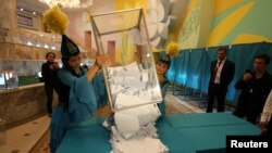 Члены избирательной комиссии опрокидывают урну с бюллетенями после закрытия избирательного участка в Алматы в день президентских выборов. 9 июня 2019 года.